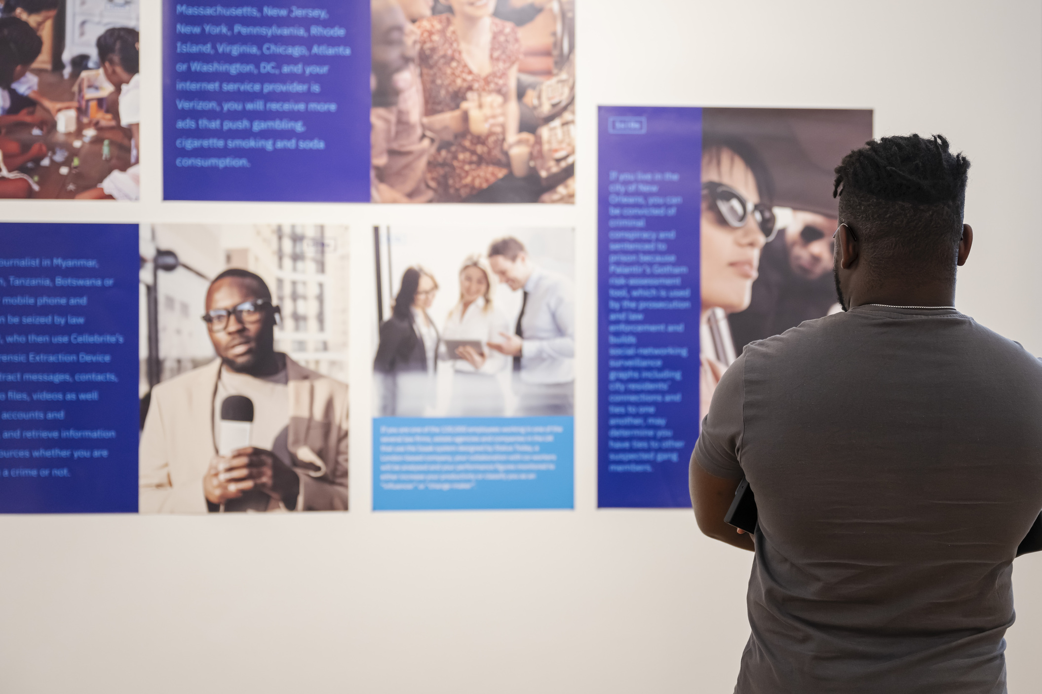 person looking at an exhibition of printed materials on the wall.